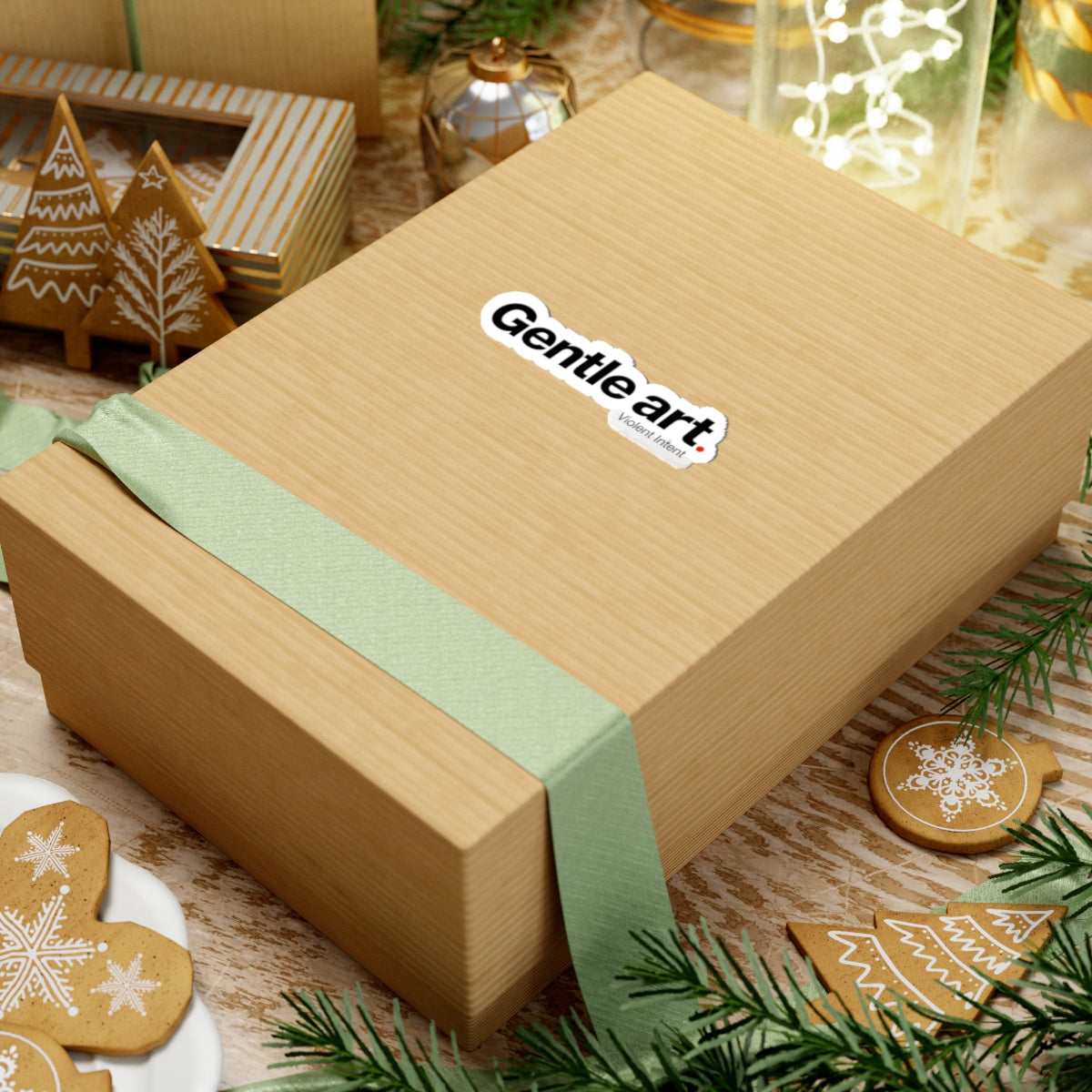 Wooden gift box with a green ribbon and 'Gentle art' label, surrounded by Christmas decorations.