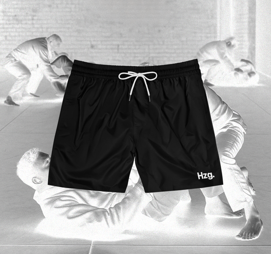 Black shorts with HZG logo on a background of black and white martial arts poses.