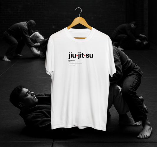 White t-shirt with 'jiu-jitsu' text on a hanger against a black and white background of people practicing martial arts.